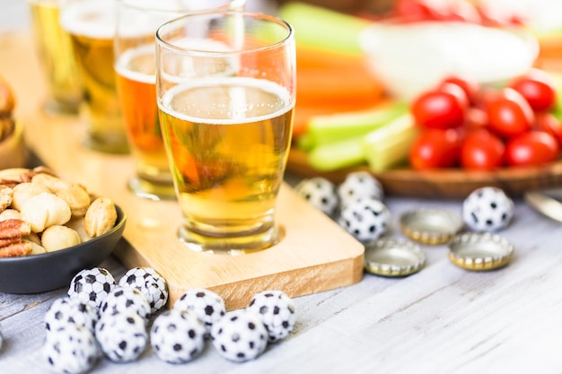 Chopes e salgadinhos em cima da mesa para festa de futebol.