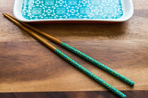 CHOPSTICKS DE BAMBU NATURAL e placa no fundo da mesa de madeira