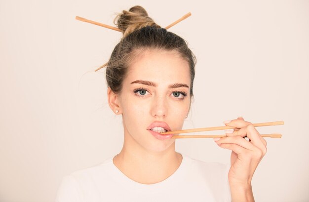 Chopsticks in der Nähe von sexy Lippen Mund sexy Frau berühren sinnliche Lippen mit Chopsticks Sushi Werbung