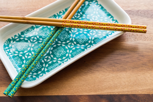 CHOPSTICKS NATURALES DE BAMBÚ y placa sobre fondo de mesa de madera