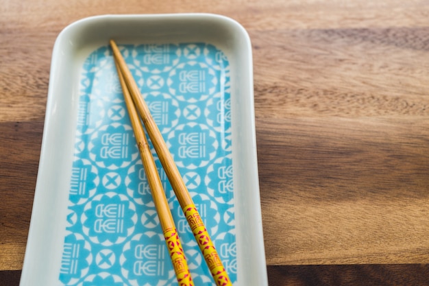 CHOPSTICKS NATURALES DE BAMBÚ y placa sobre fondo de mesa de madera