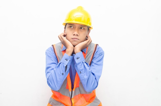 chorando triste trabalhador da construção civil masculino asiático vestindo camisa azul, colete de segurança e jaqueta amarela.