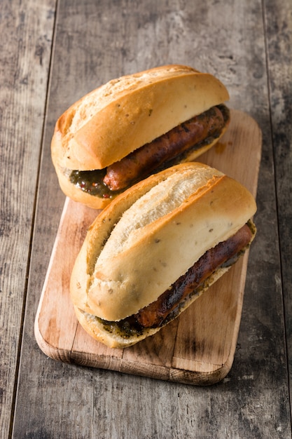 Choripan. Sanduíche tradicional da Argentina com molho de chouriço e chimichurri na mesa de madeira