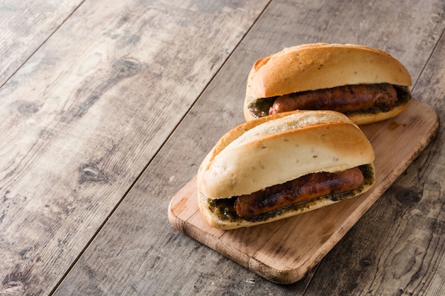 Choripan. sanduíche tradicional da argentina com molho de chouriço e chimichurri na mesa de madeira