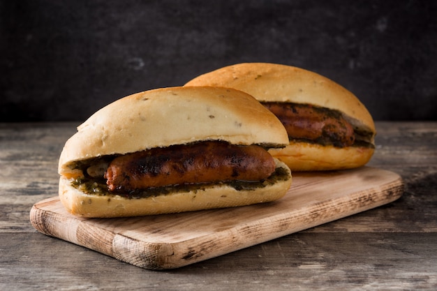 Choripan. sanduíche tradicional da argentina com molho de chouriço e chimichurri na mesa de madeira