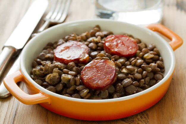 Chorizo mit Linsen auf Teller und Glas Wasser