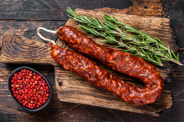 Chorizo Schweinefleisch Trockenwurst auf einem Holzbrett. Dunkler hölzerner Hintergrund. Ansicht von oben.