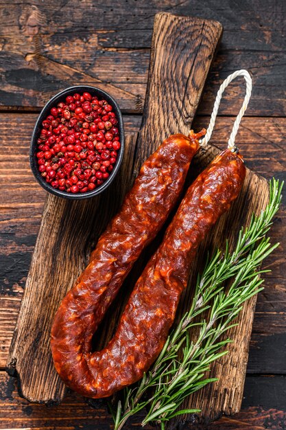 Chorizo Schweinefleisch Trockenwurst auf einem Holzbrett. Dunkler hölzerner Hintergrund. Ansicht von oben.