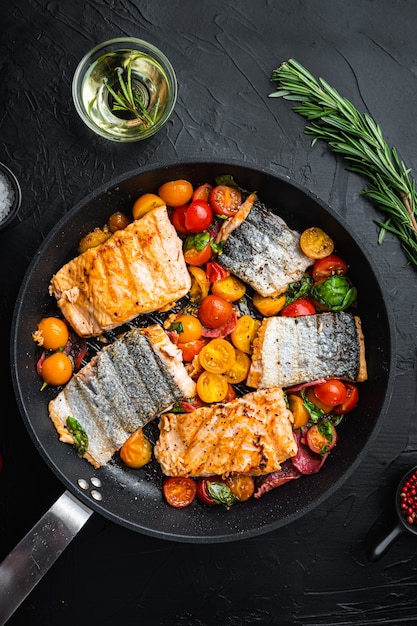 Chorizosalmon ahumado a la plancha con tomates cherry sobre fondo negro, vista superior.