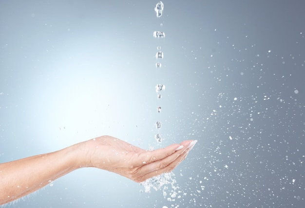 Foto chorro de agua y mano aislada en estudio sobre fondo gris para limpieza e hidratación de bienestar cuidado del cuerpo de la salud y limpieza de la mujer hidrato y lavado de manos con salpicaduras de agua para la higiene