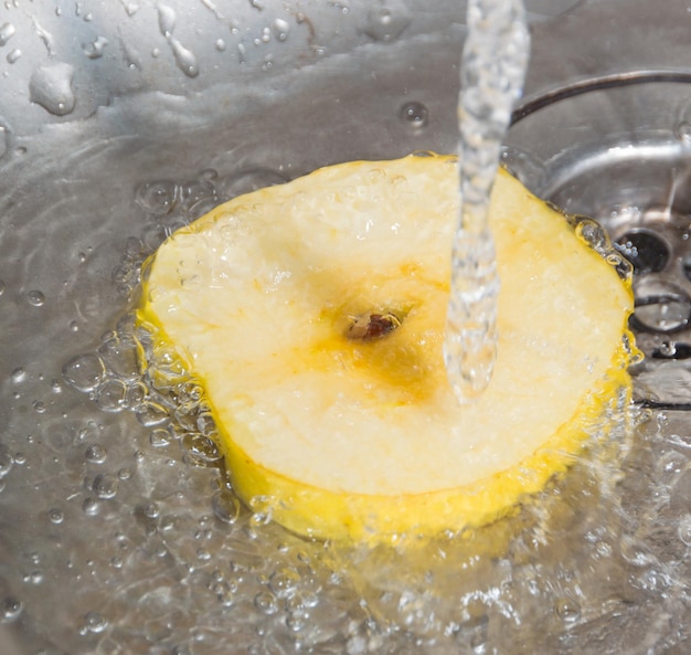 Bajo el chorro de agua y una rodaja de manzana amarilla en el fregadero.