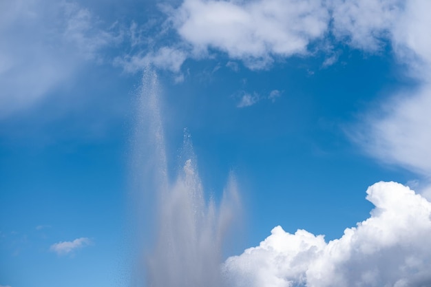 Chorro de agua sobre un fondo de cielo azul con nubes