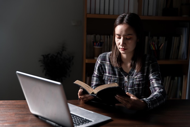 Christian concepto de tecnología en línea manos orando de cristiano con computadora digital portátil iglesia en línea en vivo para el servicio dominical hombre católico asiático están leyendo la Biblia libro y estudio en línea