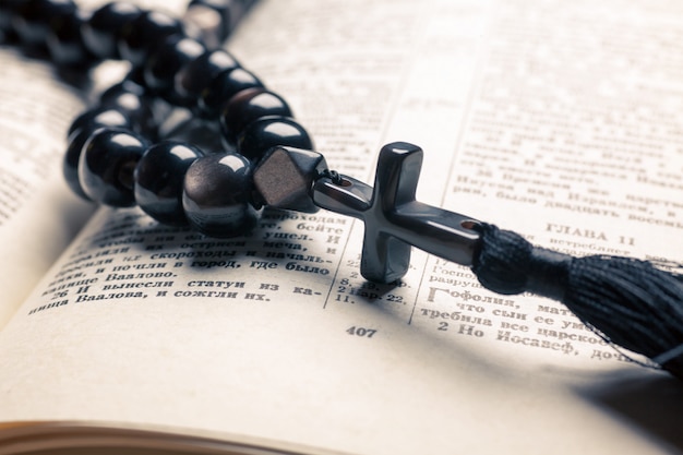 Foto christliche perlen aus schwarzem stein mit kreuz auf der bibel