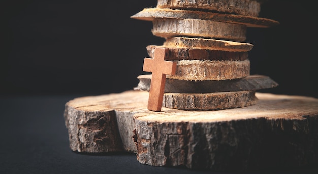 Christliches Holzkreuz auf Baumscheiben.