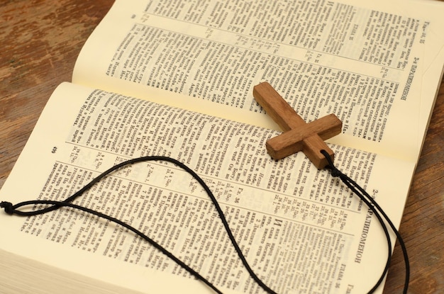 Christliches Holzkreuz mit Seil auf einer offenen heiligen Bibel