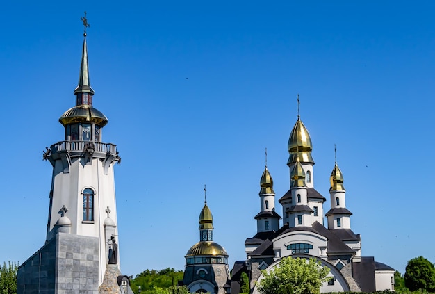 Christliches Kirchenkreuz im hohen Kirchturm für Gebetsfotografie, bestehend aus einer schönen Kirche mit Kreuz auf dem Kirchturm bis zum aufrichtigen Gebetskreuz. Der Kirchturm ist ein Kirchengebet über klarem Himmel