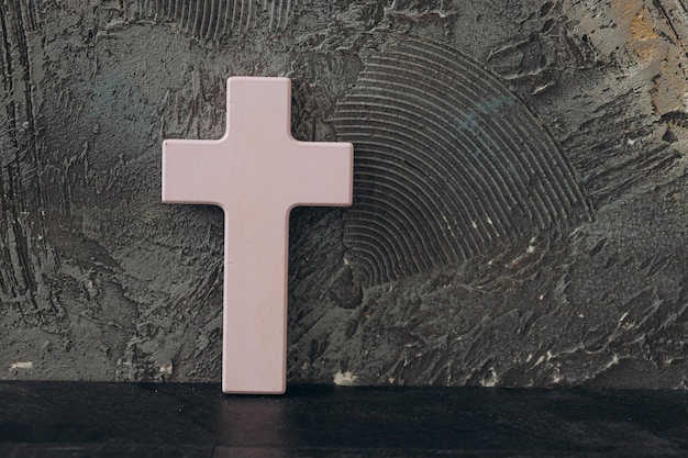 Christliches Kreuz auf einem strukturierten schwarzen Hintergrund Religionskonzept Rosa Kreuz