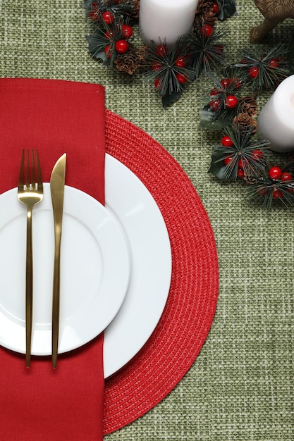 Christmas place setting with festive decor on green tablecloth flat lay