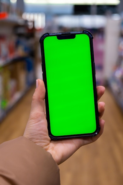 Chroma key Close-up da mão da mulher segura o telefone inteligente vertical com tela verde na loja do shopping center Shopping center Loja de departamentos Modelo de gadgets de compras on-line