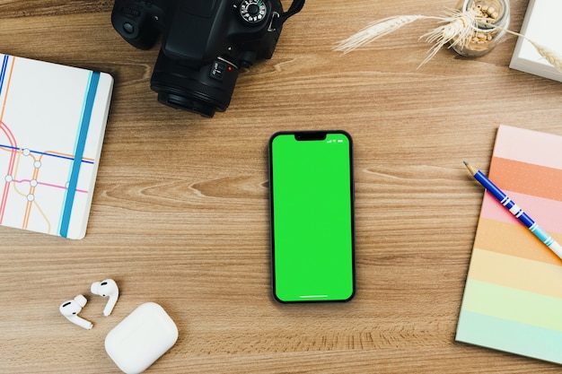 Chroma Key en la pantalla del teléfono inteligente en la mesa de madera con otros accesorios. Vista superior. Pantalla verde.