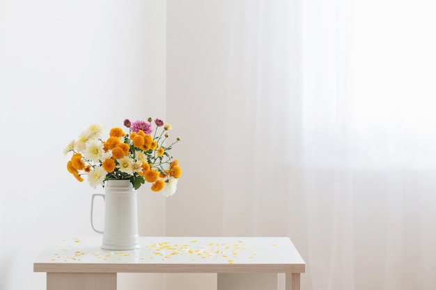 Chrysanthemenblumen im weißen Krug auf weißer Hintergrundwand