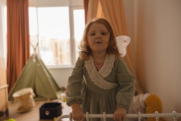 Chubby linda niña caucásica con pelo rojo usa vestido en la habitación de los niños Concepto de pasatiempo