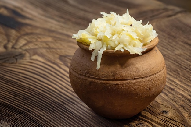 Chucrut en escabeche casero en un frasco de cerámica sobre una tabla de madera