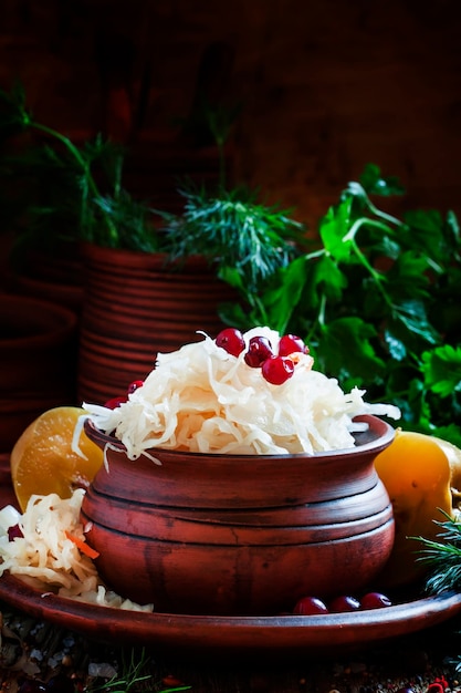 Chucrut ruso tradicional con manzanas en escabeche y arándanos en un enfoque selectivo de fondo negro de arcilla