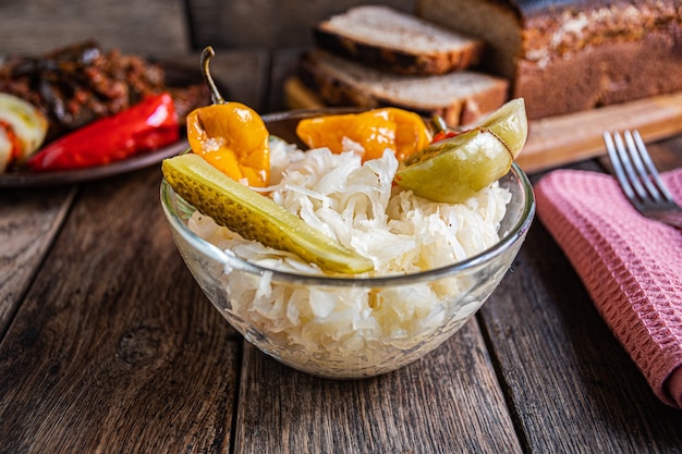 Chucrut tomate pepino y pimiento en un recipiente de vidrio sobre una mesa de madera Encurtidos caseros