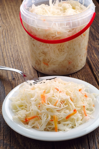 Chucrut con zanahoria en un plato y cubo de plástico