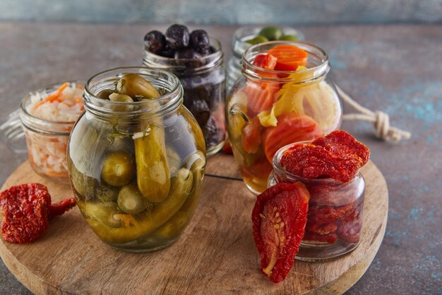 Foto chucrute, cenoura em conserva, pepino em conserva, azeitonas e azeitonas em conserva, tomate seco em potes de vidro