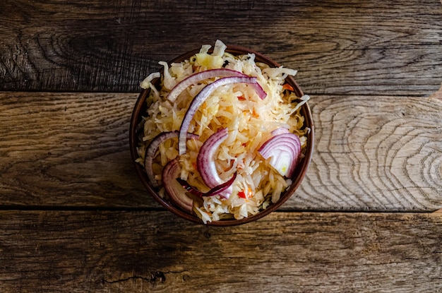 Chucrute em faiança em um fundo de madeira. Cozinhar comida fermentada caseira.