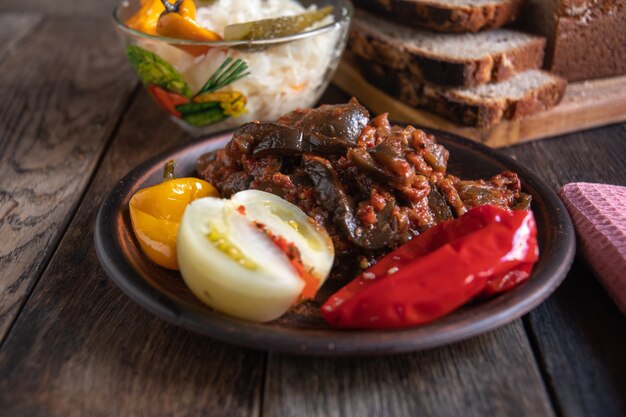 Chucrute, tomate, pepino e pimenta em uma tigela de vidro sobre uma mesa de madeira Picles caseiros