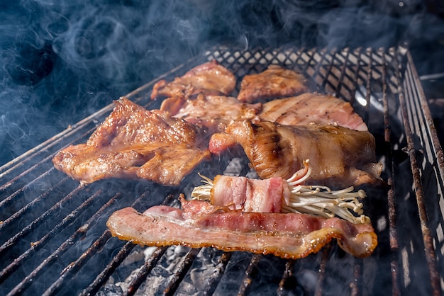 Chuleta de cerdo y enoki envuelto en tocino A la parrilla en parrilla de carbón, cultura culinaria asiática