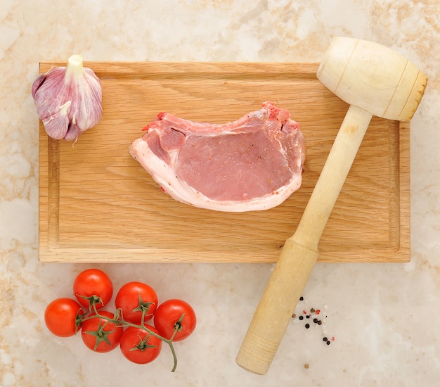 Chuleta de cerdo sobre tabla de madera con tomates