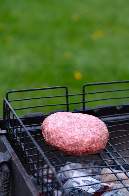 una chuleta está frita en la parrilla afuera contra el telón de fondo de un césped verde