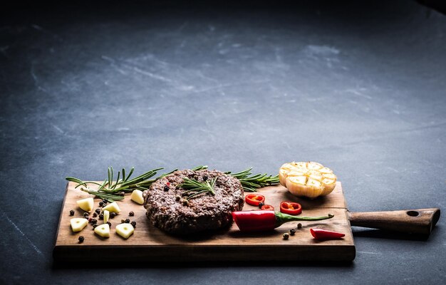 Chuleta de hamburguesa de ternera casera con hierbas y especias en el espacio de la placa de cocina de madera para el texto