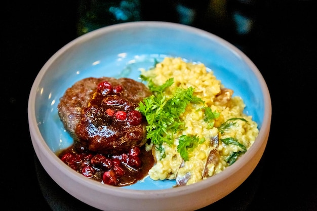 Chuleta con salsa de arándanos y risotto está en el plato