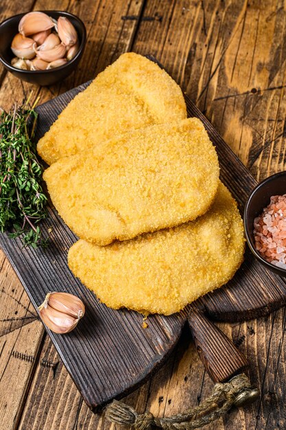 Chuletas de carne cordon bleu con pan rallado sobre una tabla de madera.