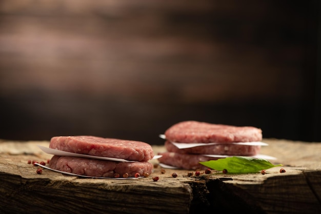 Chuletas de carne de res cruda hamburguesa y fondo de madera de pimiento rojo seco