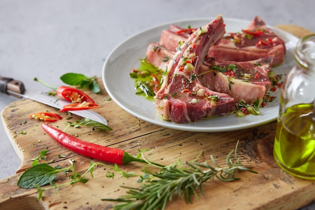 Chuletas de cordero crudas en tabla de cortar con aceite