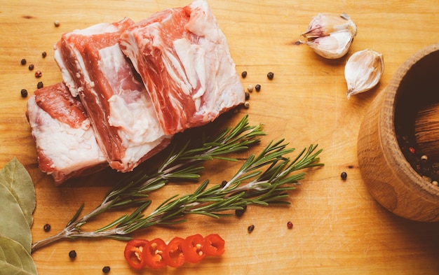 Chuletas de costilla de cerdo cruda en tabla cortada con ajo de pimienta de romero y procesamiento de fotos vintage de hoja de laurel