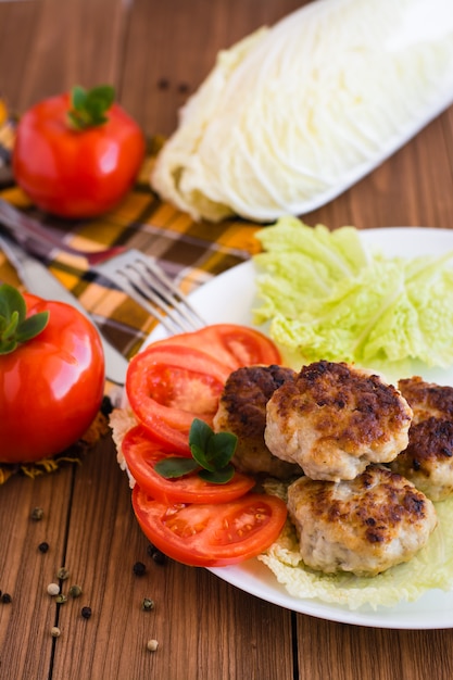 Chuletas fritas y verduras frescas en una mesa de madera