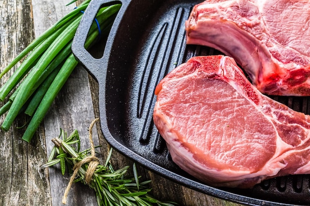 Chuletas de león de cerdo ecológico de corte grueso en sartén de hierro fundido.