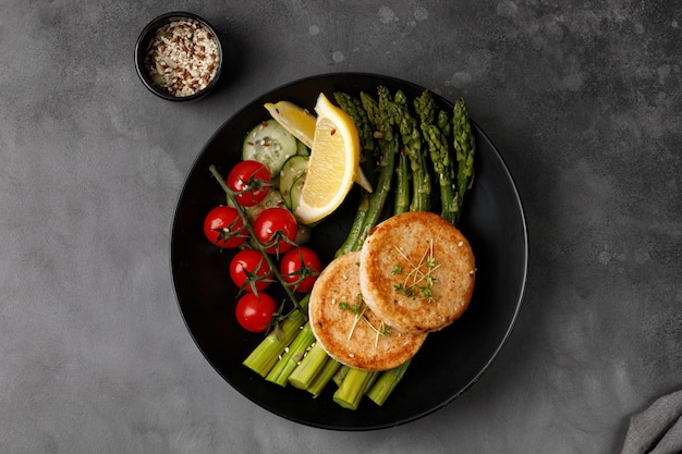 Chuletas de pescado o empanadas de chuletas de pollo con espárragos hervidos y tomates cereza idea de cena