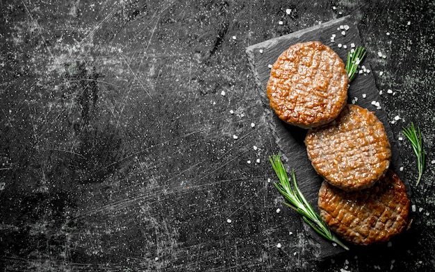 Chuletas en un tablero de piedra negra con romero