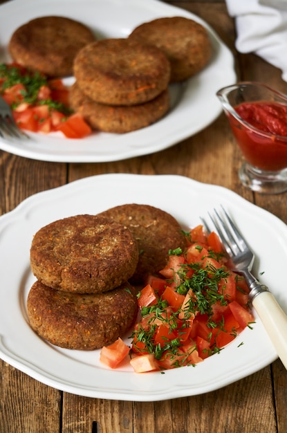 Chuletas de trigo sarraceno con ensalada de tomate fresco en un plato blanco