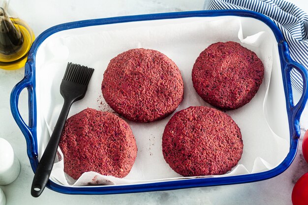 Chuletas veganas crudas para hamburguesas sin carne en una bandeja para hornear sobre una mesa