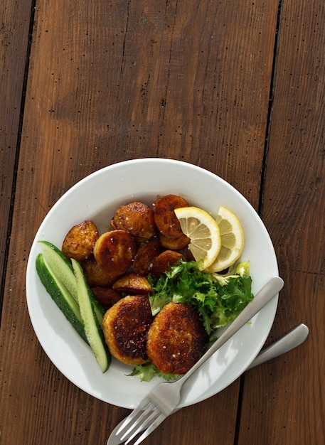 Chuletas vegetarianas frescas con papas nuevas y ensalada en una mesa de madera